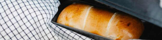 Image if a person using a cloth to take bread out of an oven