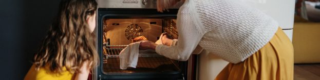 image of mother and daughter cooking together and putting something in the oven
